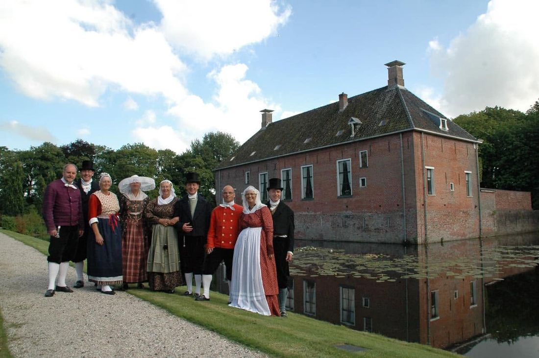 Dansgroep in historische Groninger klederdracht voor een borg met gracht