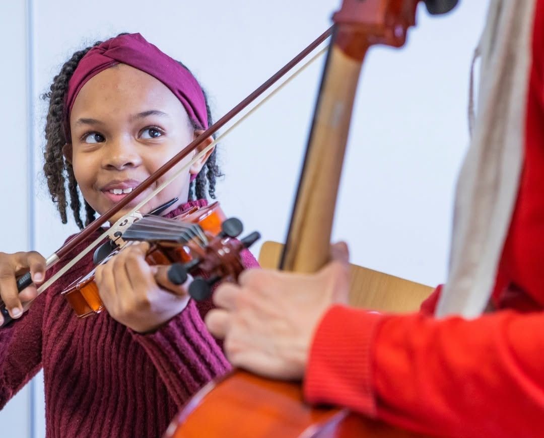 Meisje krijgt vioolles en speelt viool naast haar docent
