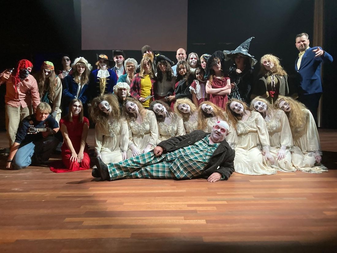 Theatergezelschap in kostuum poseert op het podium na een voorstelling